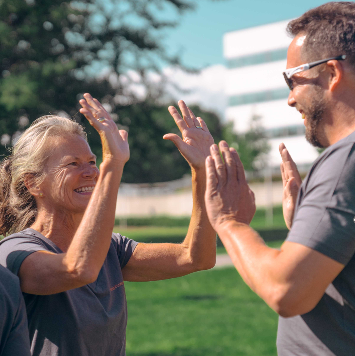 To kollegaer som gir hverandre en high five utendørs